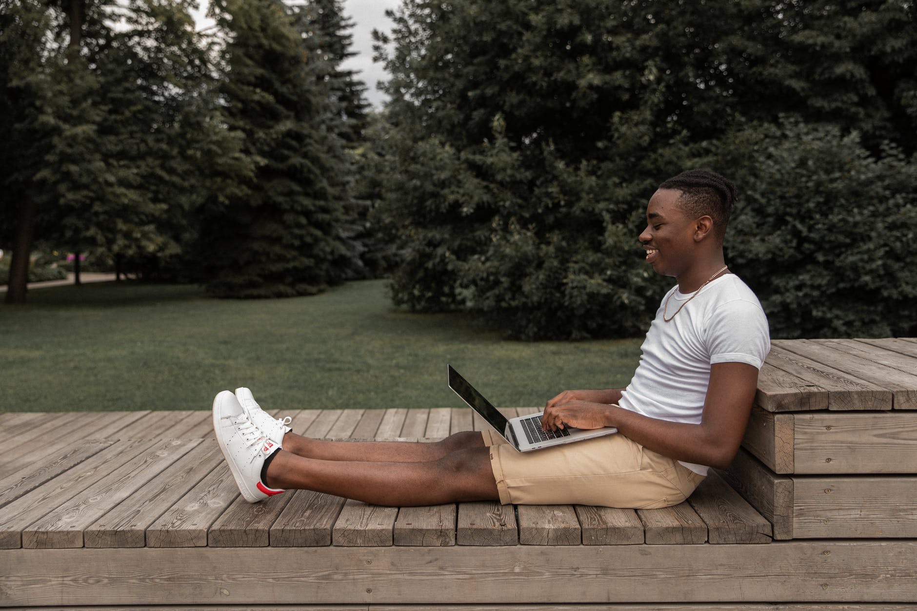 happy black man with laptop in park